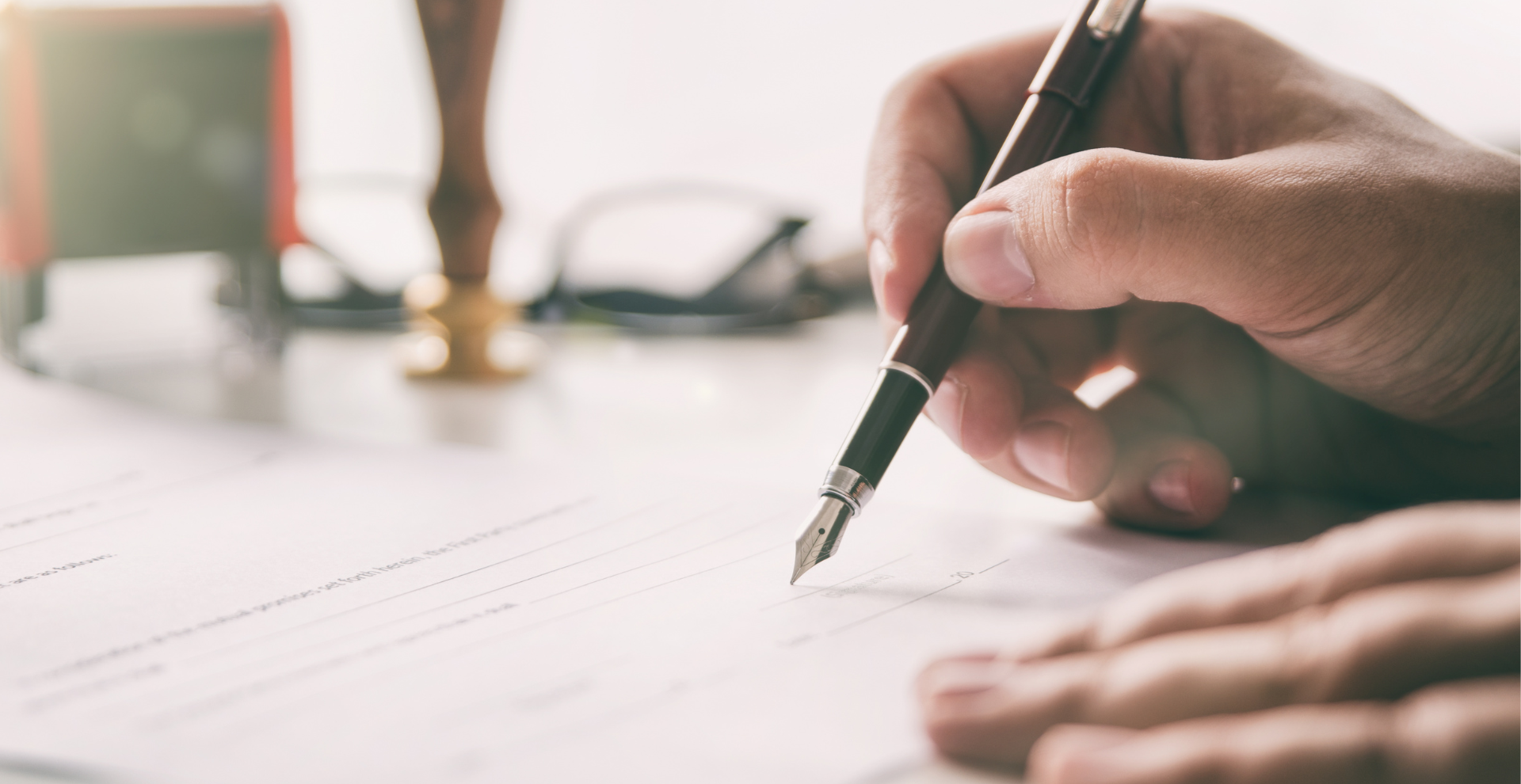 personne qui signe un papier avec un stylo plume